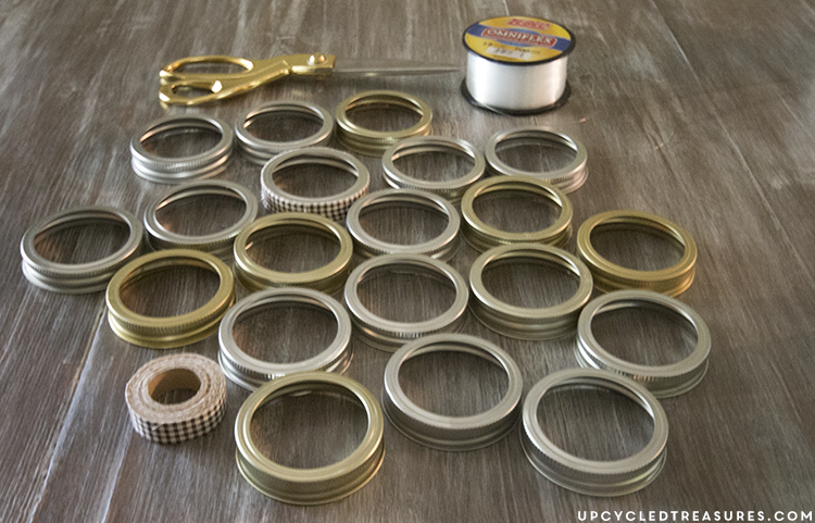 See how easy it is to create this rustic fall mason Jar lid pumpkin using canning lids, fabric tape, fishing line and a stick!