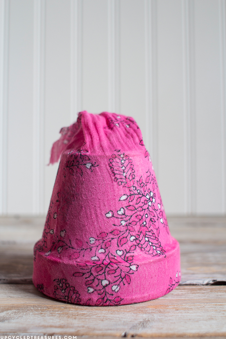 Old planter covered with pink flower designed scarf seams at the bottom. MountainModernLife.com