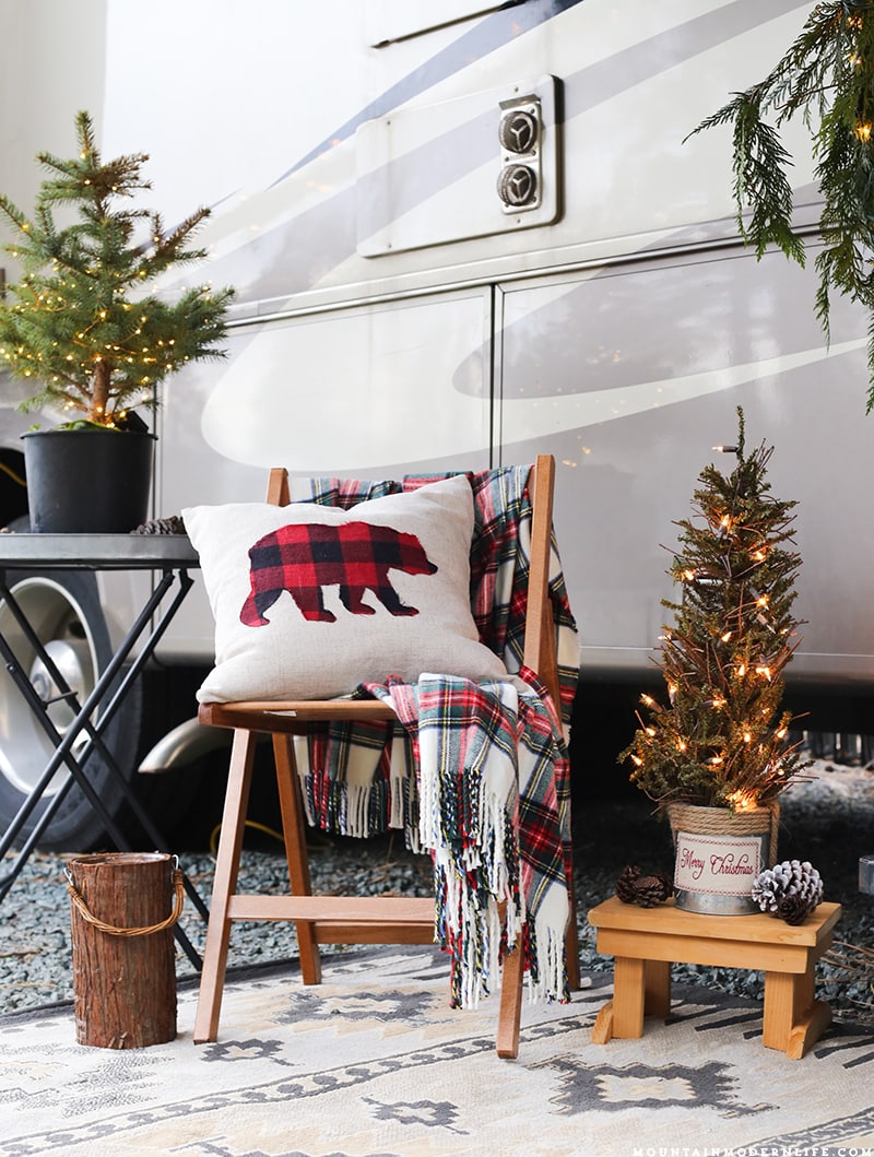 Bear pillow resting on chair outside the front of RV with Christmas decorations | MountainModernLife.com